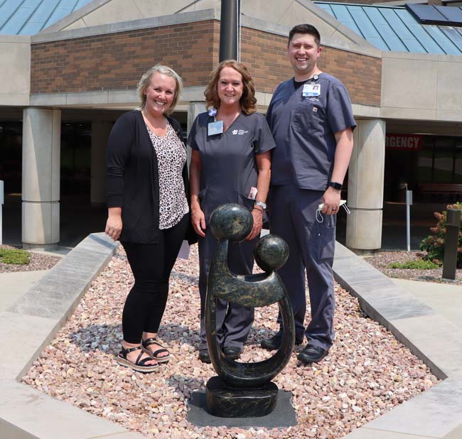 HCH nurses posing next to the Daisy statue in front of the hospital