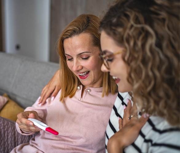 A woman showing her friend a positive pregnancy test