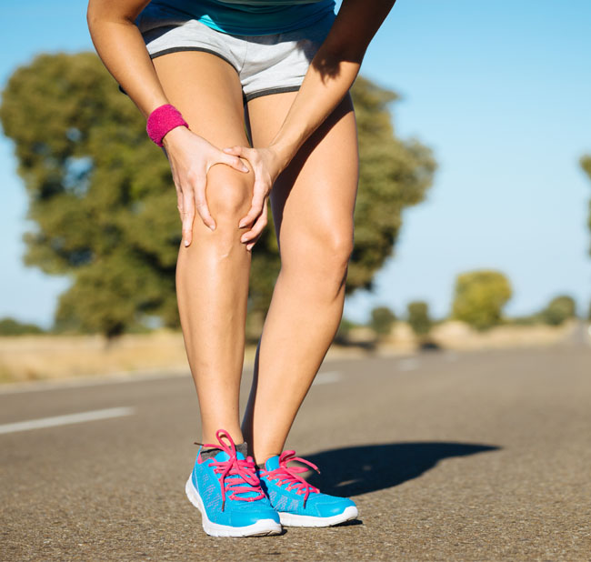 Runner holding her knee in pain