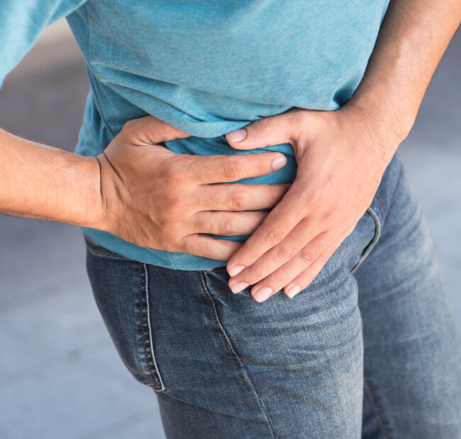 Hand grabbing side of hip indicating pain area