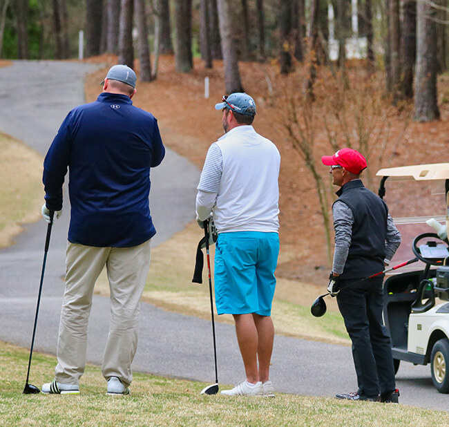 Jiffy Knee replacement men standing by cart path on golf course looking ahead.