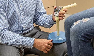 Jiffy Knee replacement surgeon Dr. Clay Strong uses an anatomical knee model to show a patient how an implant can be used to replace a damaged joint