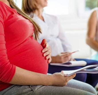 expectant mother with a hand on her belly at a prenatal class