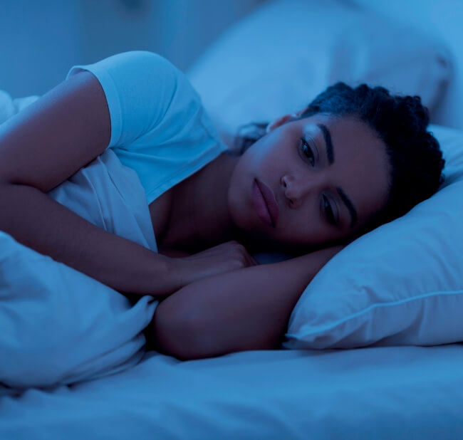 Women laying in bed at night struggling to sleep